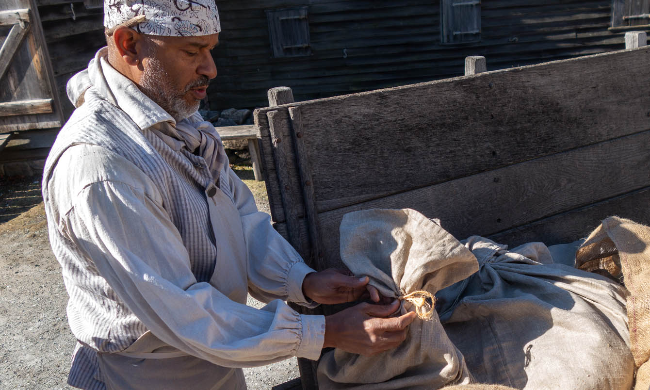 An actor portrays the work of a miller at Philipsburg Manor